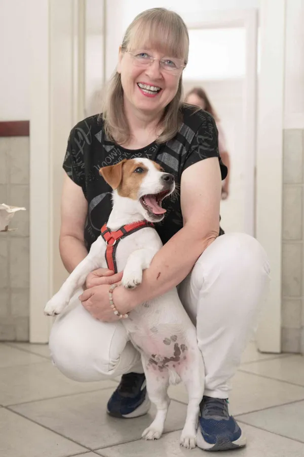 Lächelnde Frau hält einen Jack-Russell-Welpen im Arm